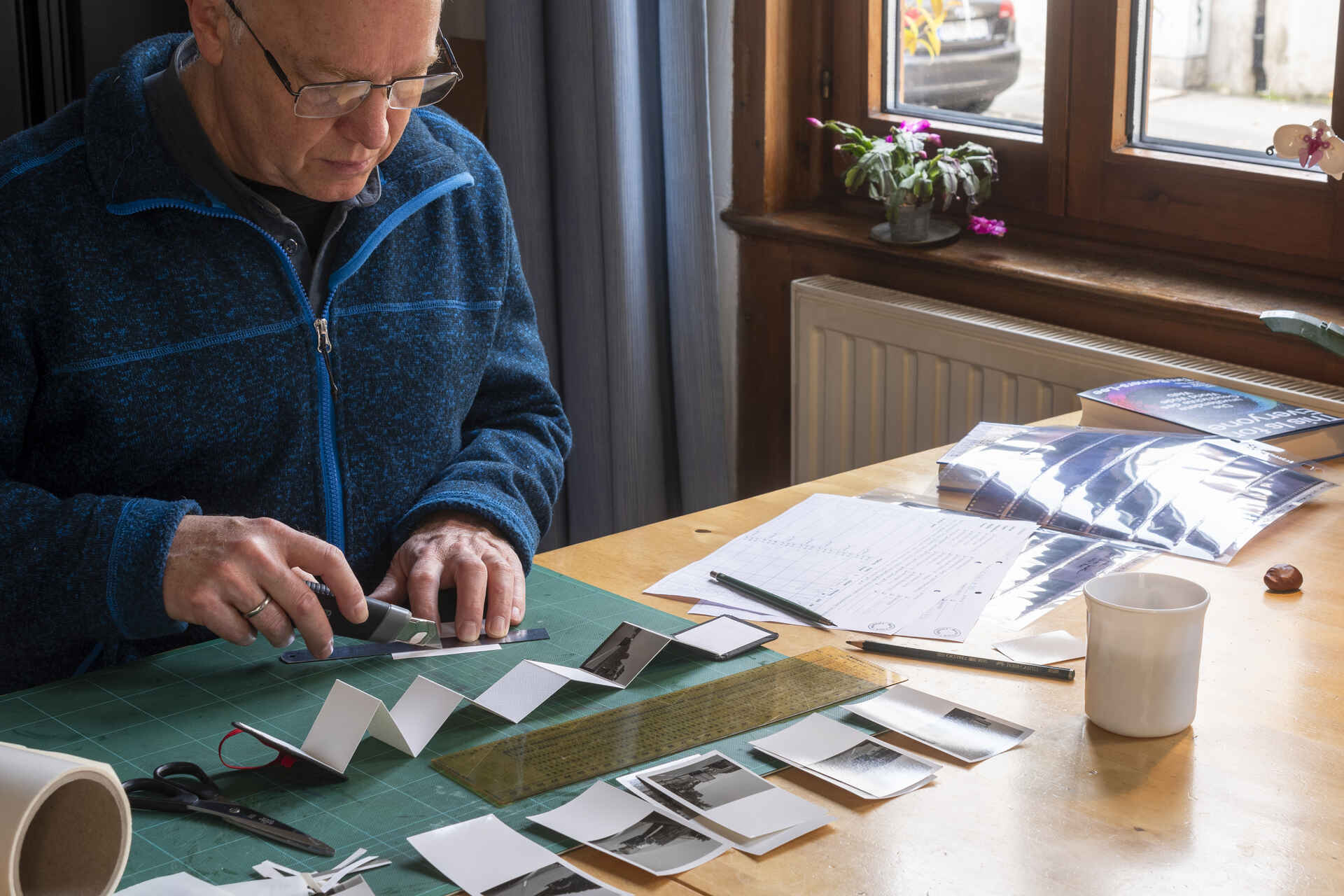 Beschneiden des Prints (Foto: Martin Frech, 10/2025) Farbfoto: Das Bild zeigt eine Person beim Beschneiden einer Fotografie. (Foto: Martin Frech, 10/2025)