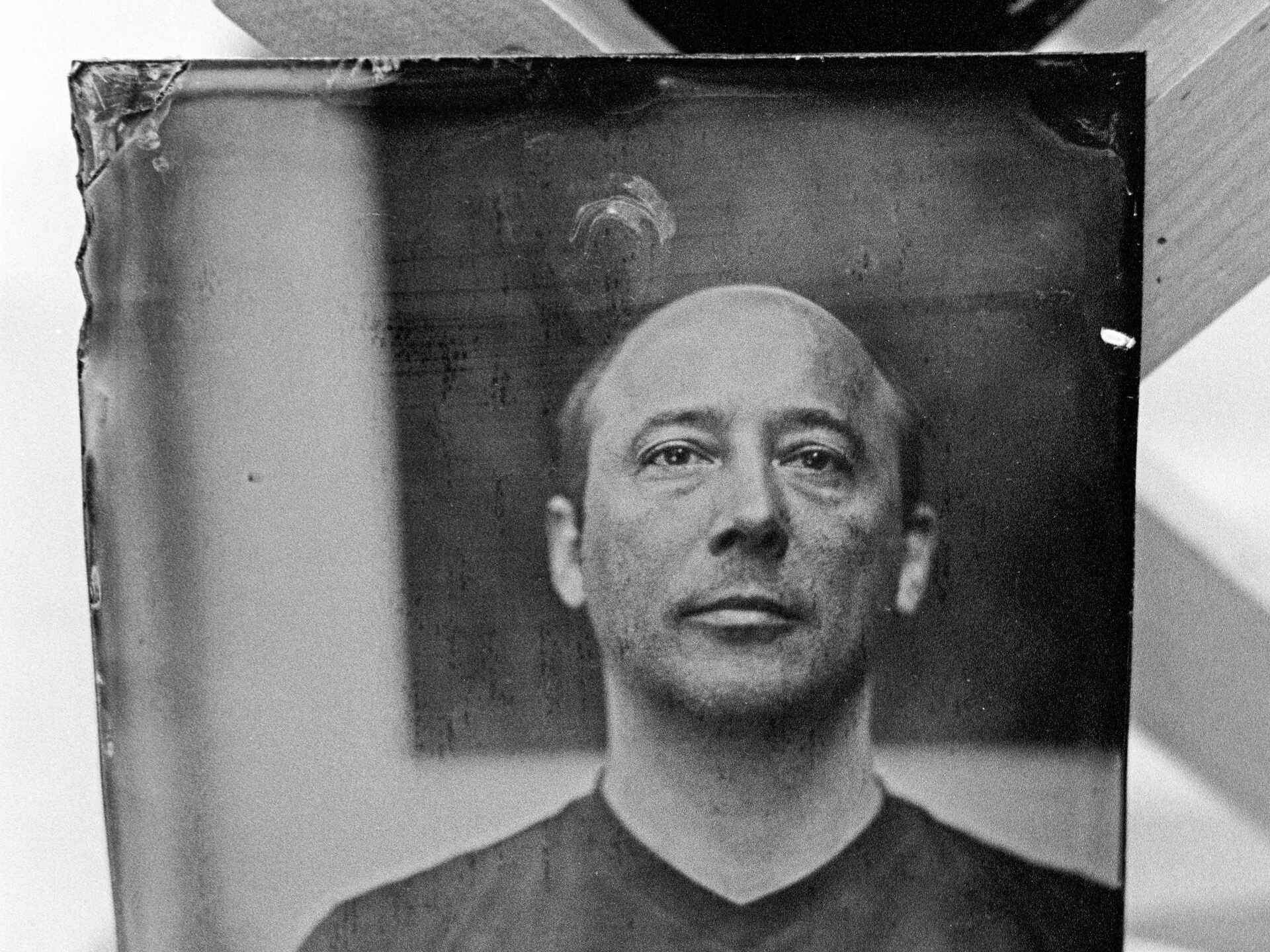 Schwarzweißbild: Die Glasplatte mit dem Portrait eines Mannes, aufgenommen im Nassen Kollodiumverfahren, trocknet. (Foto: Martin Frech, 4/2011)