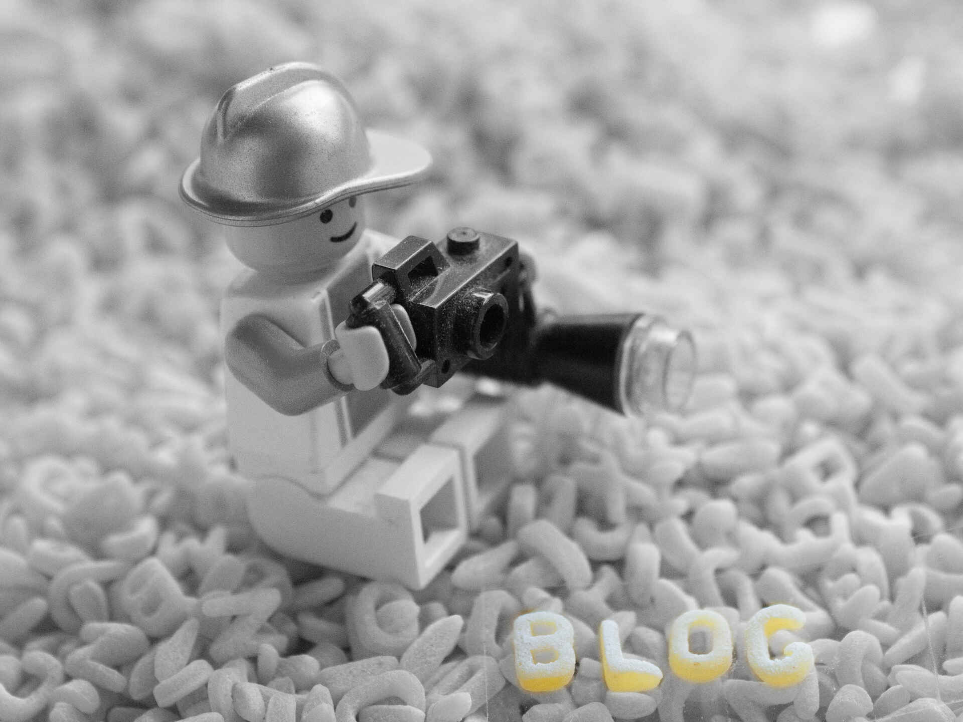 Farbbild (born-digital): Lego-Figur eines Fotografen sitzt auf einem Haufen Buchstabennudeln. (Foto: Jonathan Frech, 8/2025)