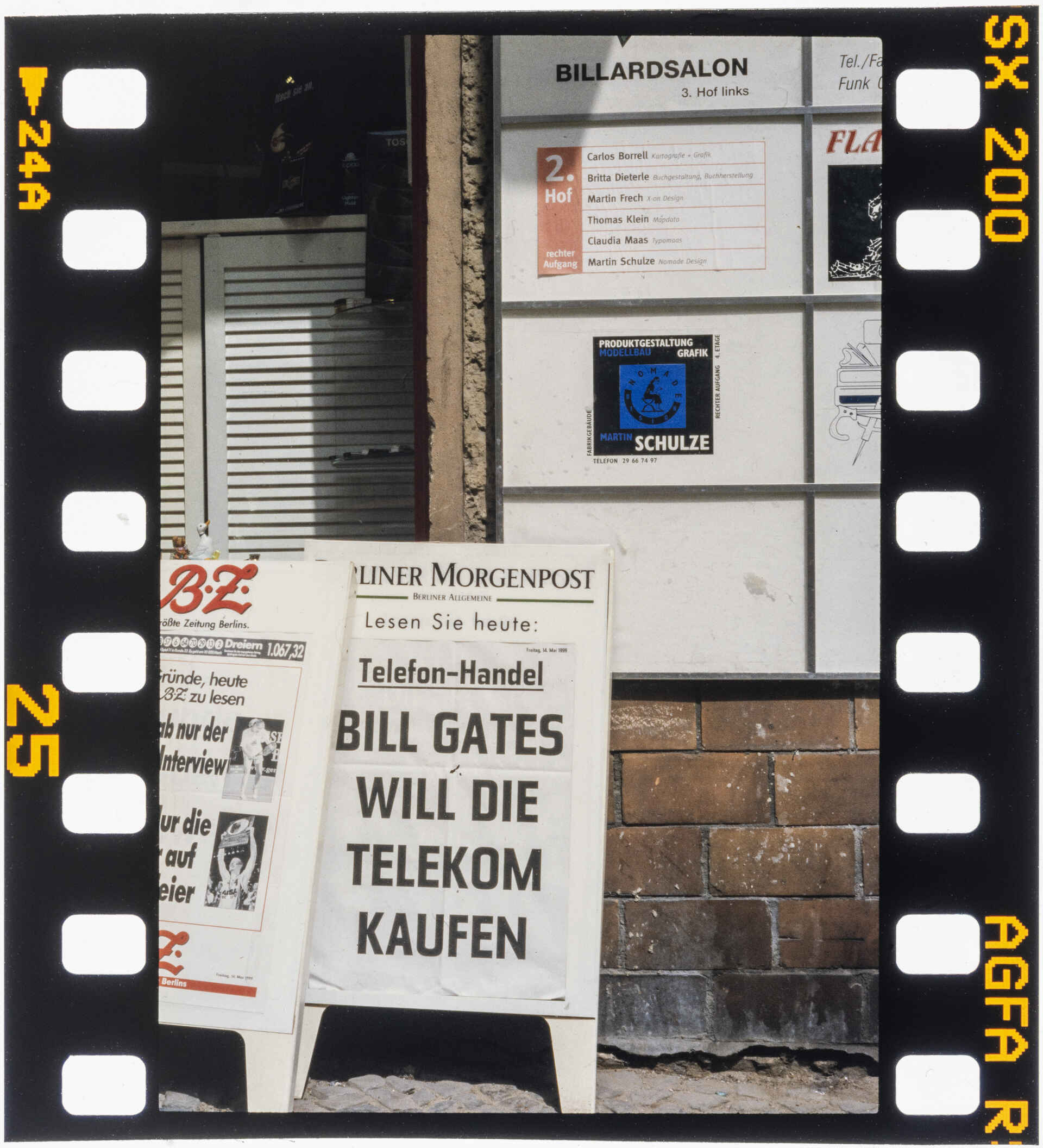 Bill Gates war 1999 noch der CEO von Microsoft und die ›Deutsche Telekom‹ seit November 1996 eine Aktiengesellschaft. (Foto: Martin Frech, 5/1999) Farbbild (DSLR-Scan vom Agfa-RSX-200-Farbdia): Werbeaufsteller der Tageszeitung Berliner Morgenpost auf der Boxhagener Straße in Berlin (Friedrichshain) mit der Schlagzeile ›Bill Gates will die Telekom kaufen‹. Im Hintergrund an einer Hauswand das Firmenschild von ›Martin Frech | X-on Design‹.