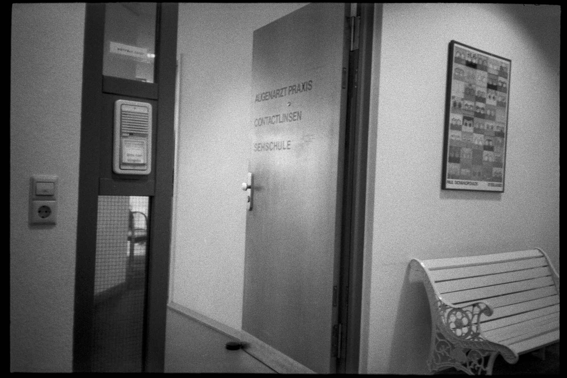 Schwarzweißbild (digitalisiert vom Adox-CHS-II-Kleinbild-Negativ): Tür einer Augenarztpraxis.
