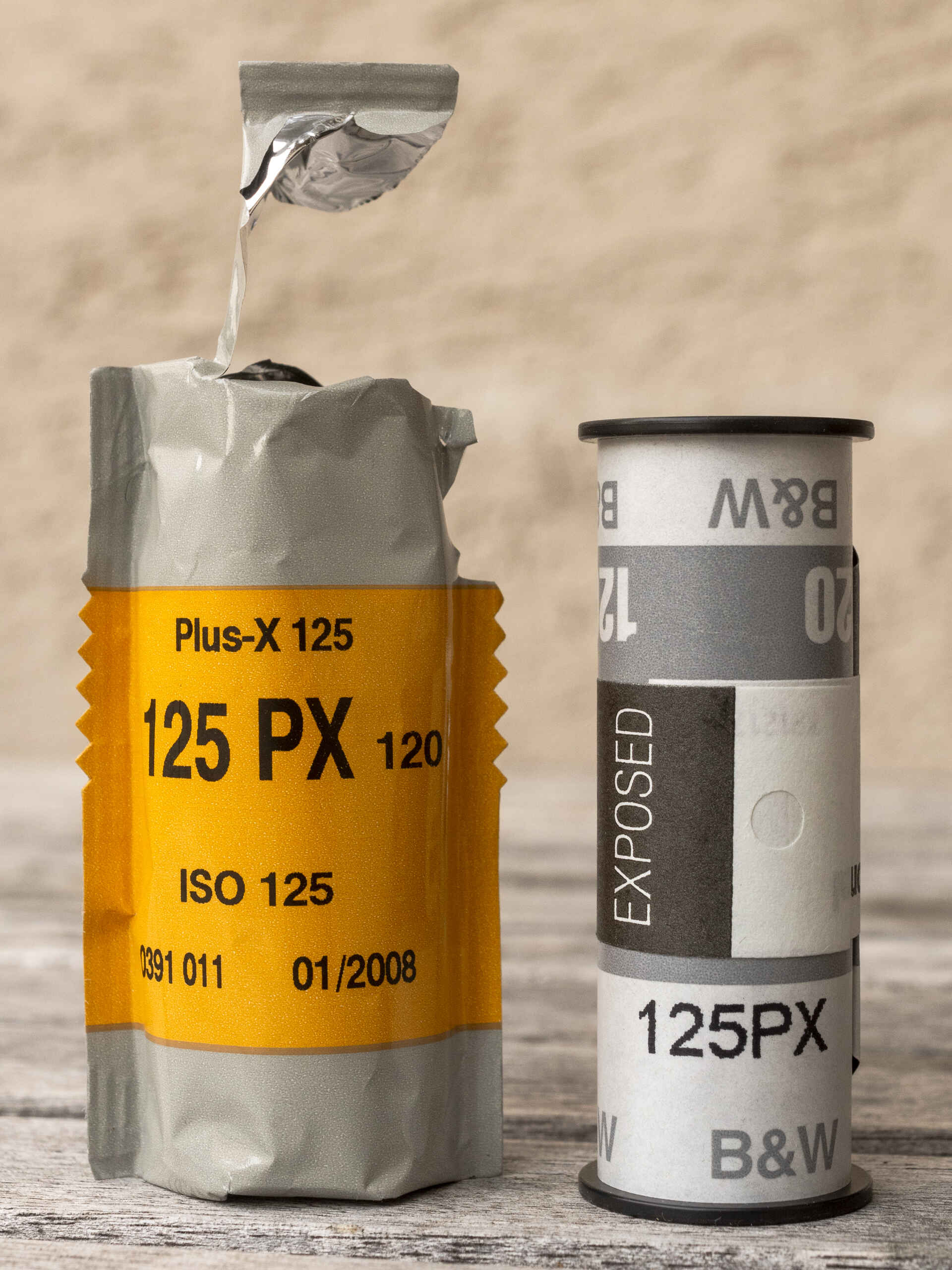 Farbbild (born-digital): Ein belichteter 120er-Rollfilm Kodak Plus-X neben seiner Umverpackung. (Foto: Martin Frech, 9/2025)