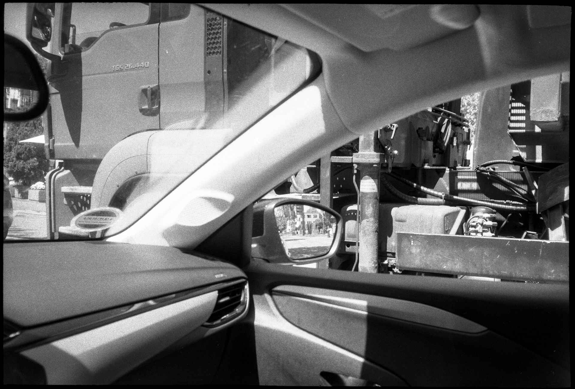 Moment im Anthropozän (Foto: Martin Frech, 5/2026) Schwarzweiß (DSLR-Scan vom Kleinbild-Negativ): LKW auf der Nebenspuhr durch das offene Beifahrerfenster gesehen.