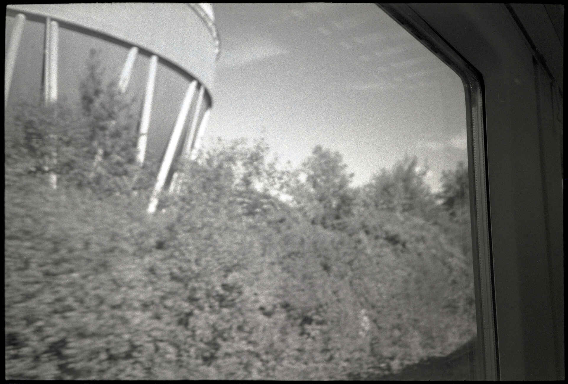 ›Gaskugel‹, Reutlingen (Foto: Martin Frech, 9/2026) Schwarzweißbild (digitalisiert vom Ilford-Delta-400-Kleinbild-Negativ): Kugelgasbehälter der FairEnergie Reutlingen im Stadtteil Betzingen, aufgenommen bei der Vorbeifahrt aus dem Fenster des Regionalzugs.