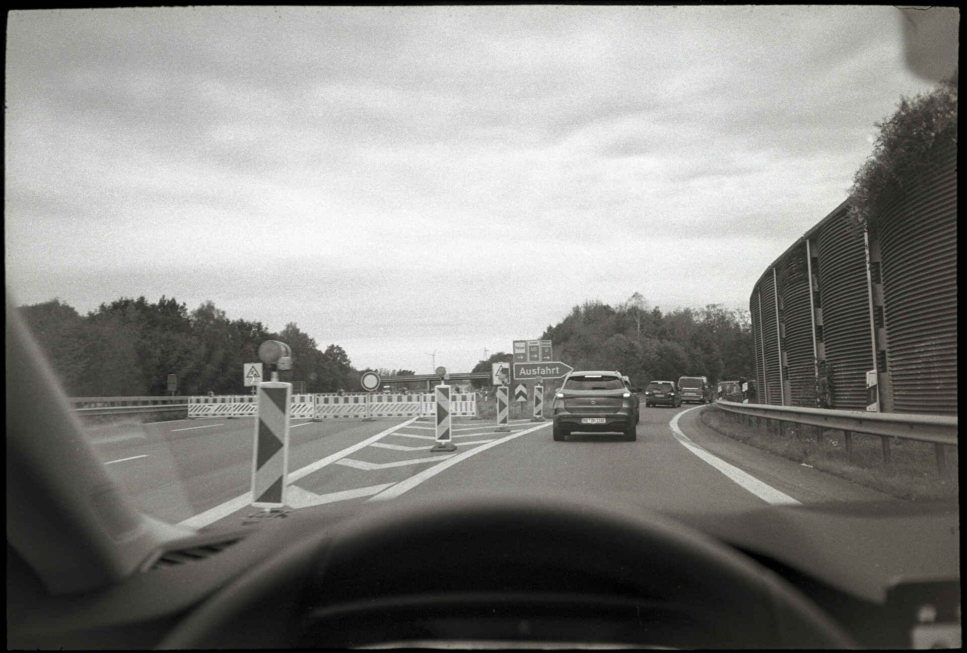 Vom Abend des 25. September bis zum Morgen des 28. September 2026 war die A1 zwischen Bramsche und Rieste wegen des Abreißens einer Brücke in beiden Richtungen gesperrt – wie ich später erfuhr. (Foto: Martin Frech, 9/2026) Schwarzweißbild (digitalisiert vom Kodak-Tri-X-Kleinbild-Negativ): Blick aus dem fahrenden Pkw auf einer Ausfahrt der voll gesperrten Autobahn A1 bei Bramsche.