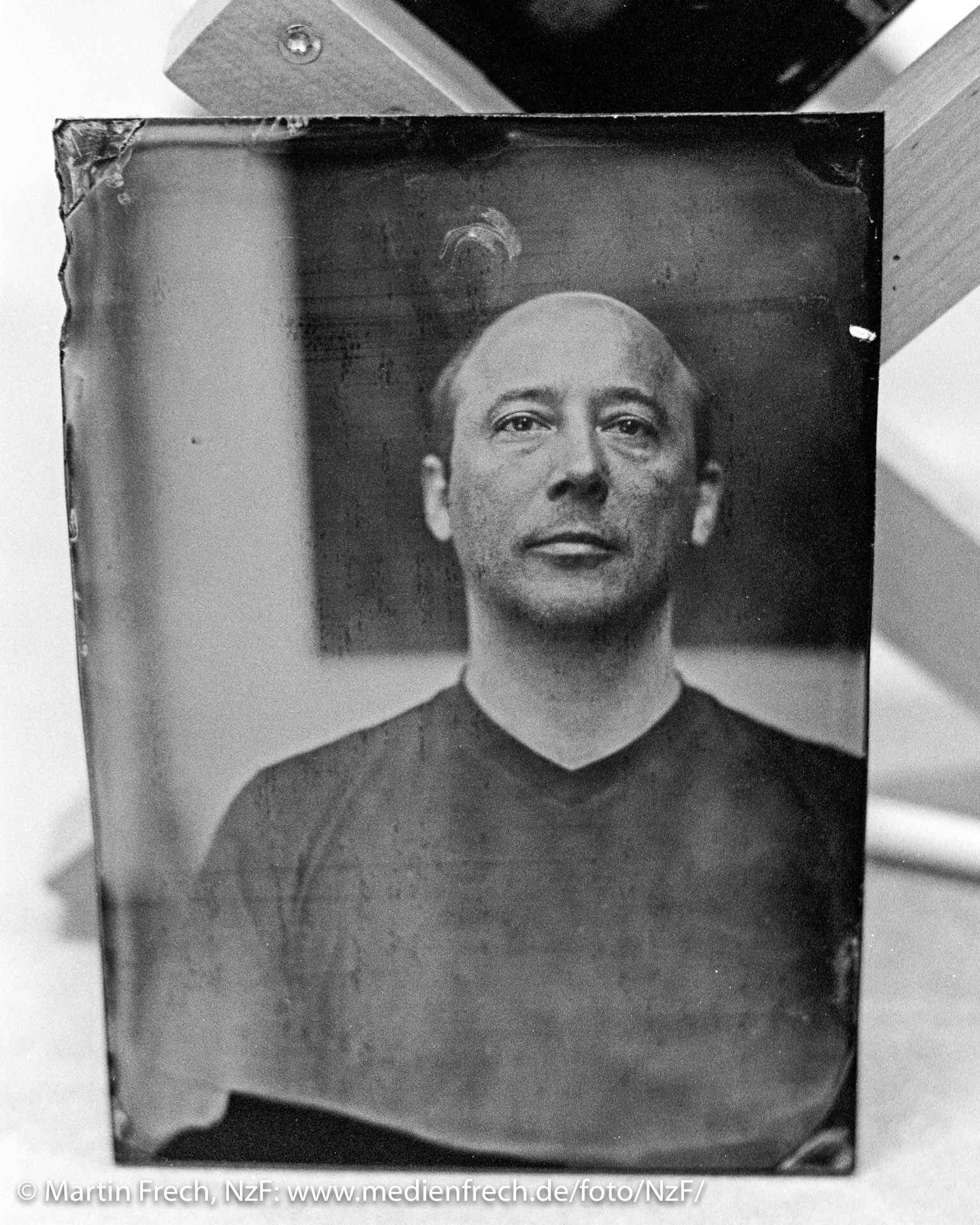 Schwarzweißbild: Ein Glasplatten-Negativ (Ambrotypie) mit dem Portrait eines Mannes steht kurz nach der Entwicklung neben dem Trockengestell. (Alle drei Fotos: Martin Frech, 2011)