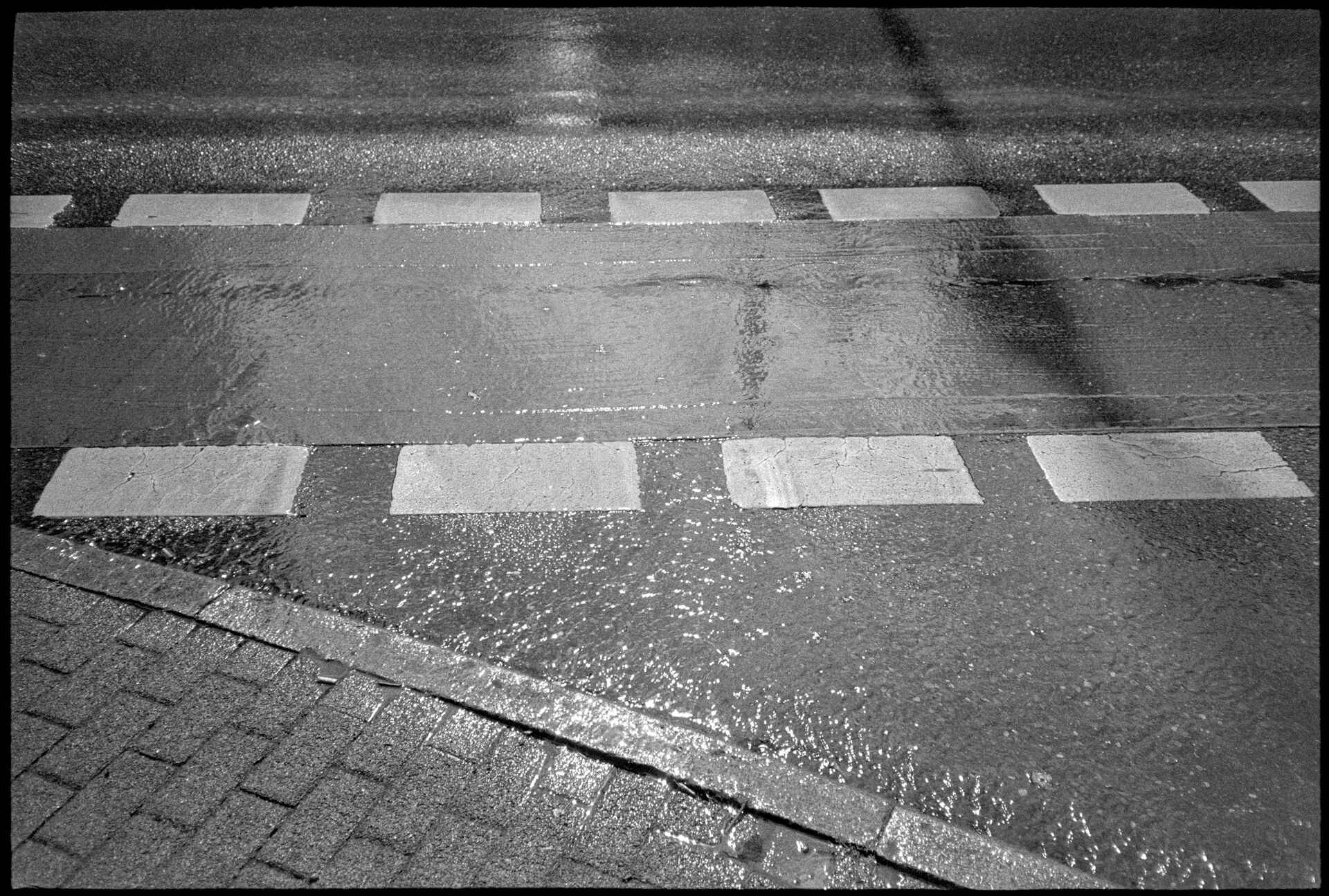 Schwarzweißbild (digitalisiert vom Lomo-Kino-Berlin-Kleinbild-Negativ): Regen auf der Konrad-Adenauer-Straße in Reutlingen.