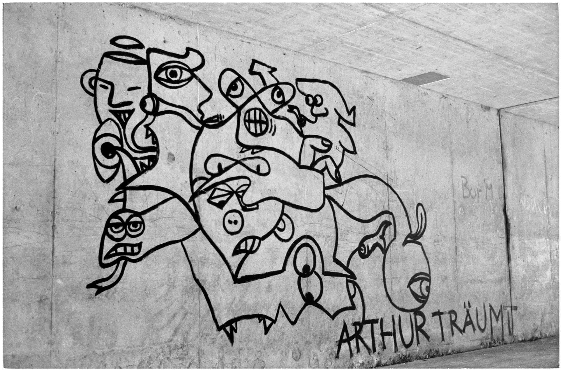 Schwarzweißbild (Scan eines FP4-Negativs): Graffiti auf Beton ›Arthur träumt‹ in einer Unterführung in Tübingen.