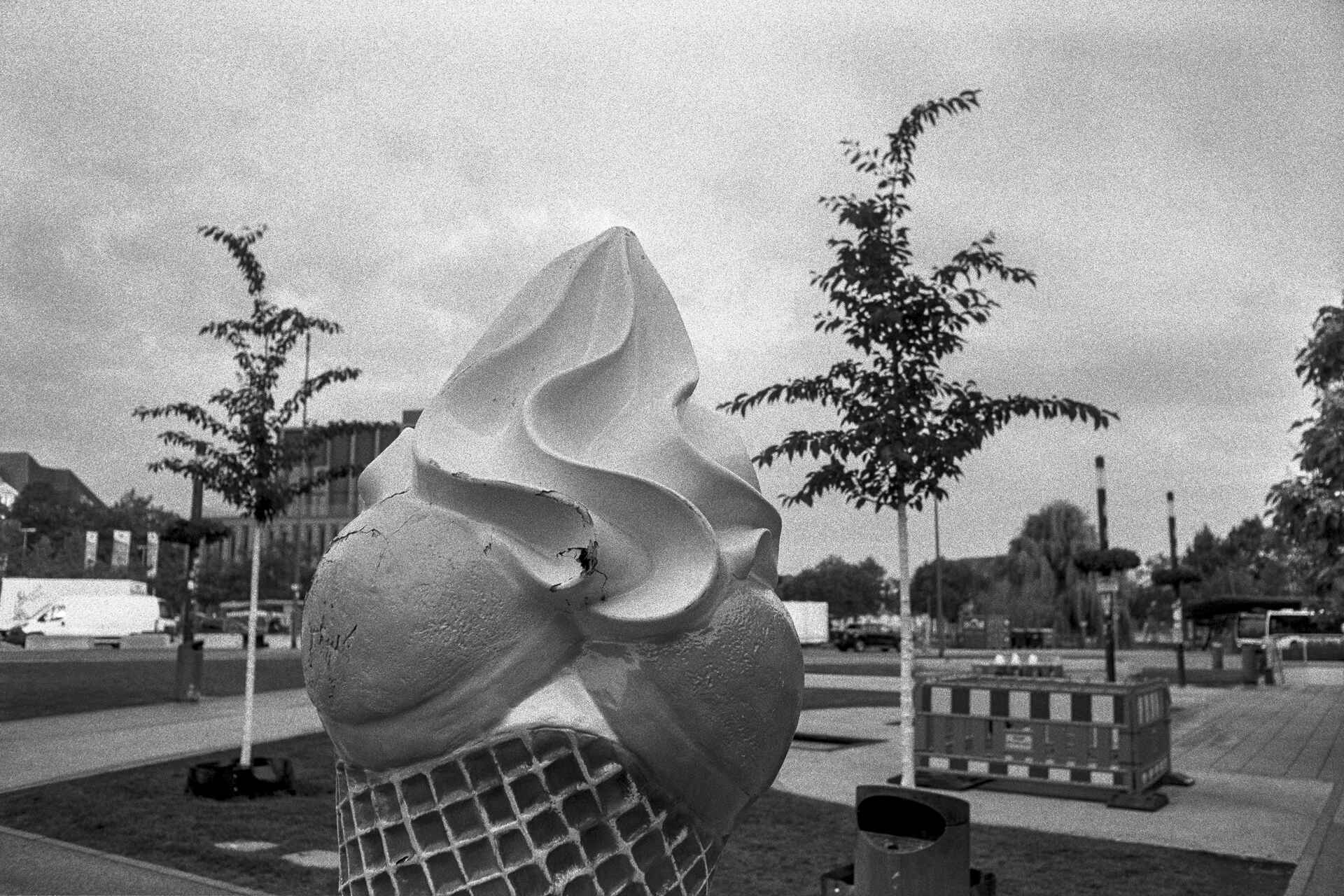 Das ewige Eis. Schwarzweißbild (digitalisiert vom HP5-Kleinbild-Negativ): Eine überdimensionierte Eistüte als Werbung vor einer Eisdiele in Reutlingen am Tübinger Tor.