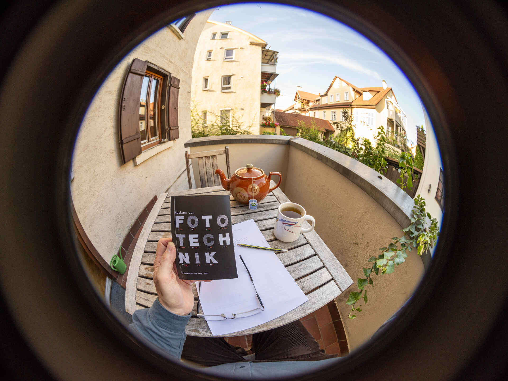 Farbfoto (Fischauge): Eine Hand hält das Buch ›Notizen zur Fototechnik‹ von Peter Jenny vor die Kamera. (Foto: Martin Frech, 9/2025)