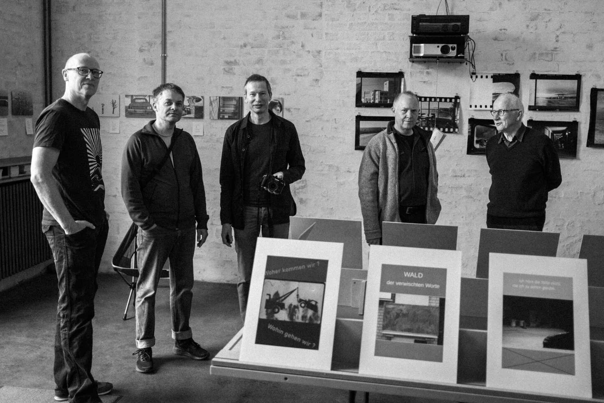 Schwarzweißbild (born-digital): Arnd Brückmann, Tommy Schmid, Dirk Jahn, Martin Frech und Günter Weckwarth-Sänger, die Macher der Ausstellung ›Bilder einer anderen Natur‹, in der schaelpic photokunstbar, Köln (Foto: Ken Werner, 5/2025)