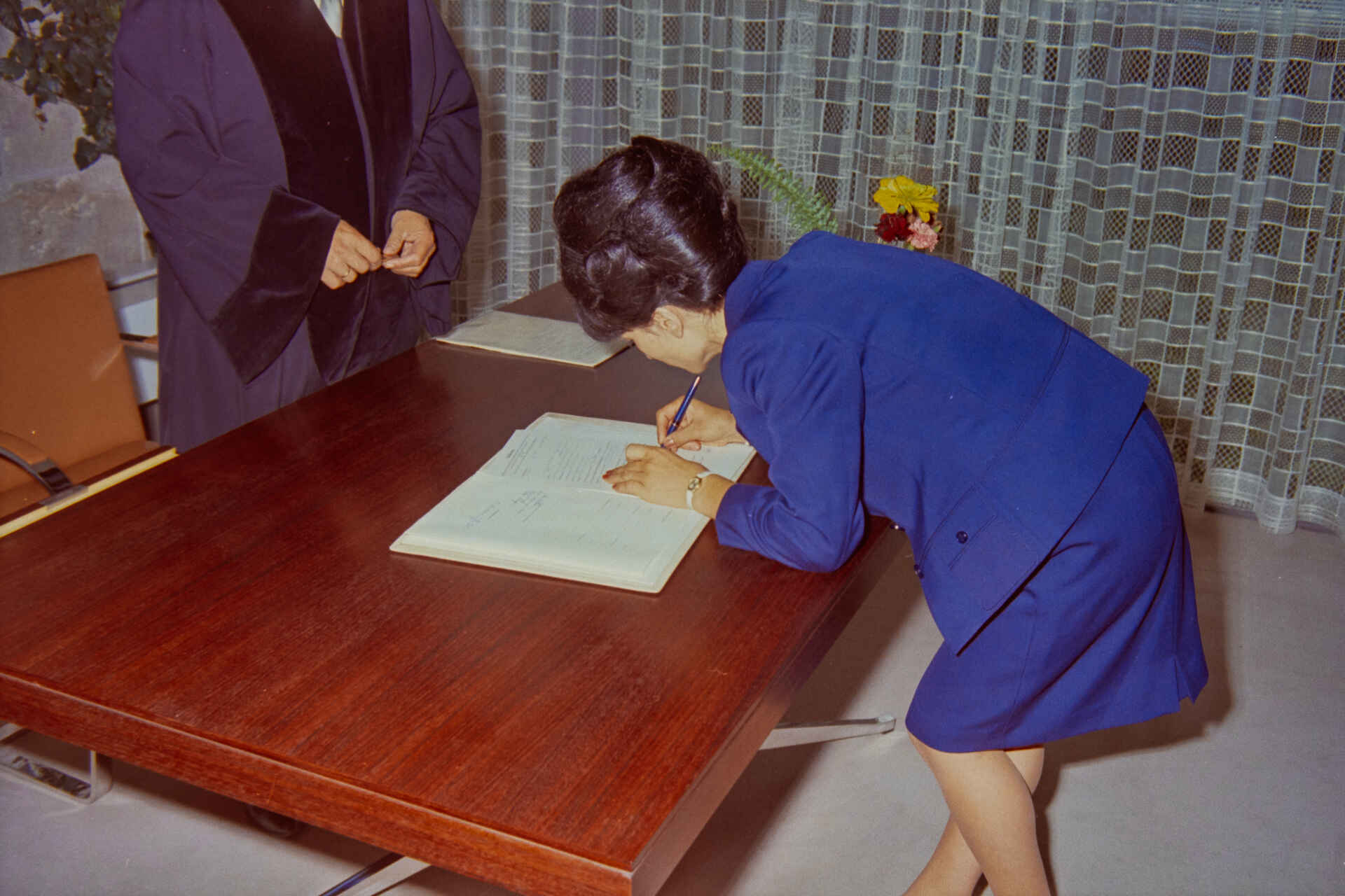 Szene auf dem Standesamt der Stadt Reutlingen (Foto: StadtA Rt./Dohm, 1967) Farbbild: Eine Frau unterschreibt eine Urkunde im Beisein einer Amtsperson. (Foto: StadtA Rt./Dohm, 1967)