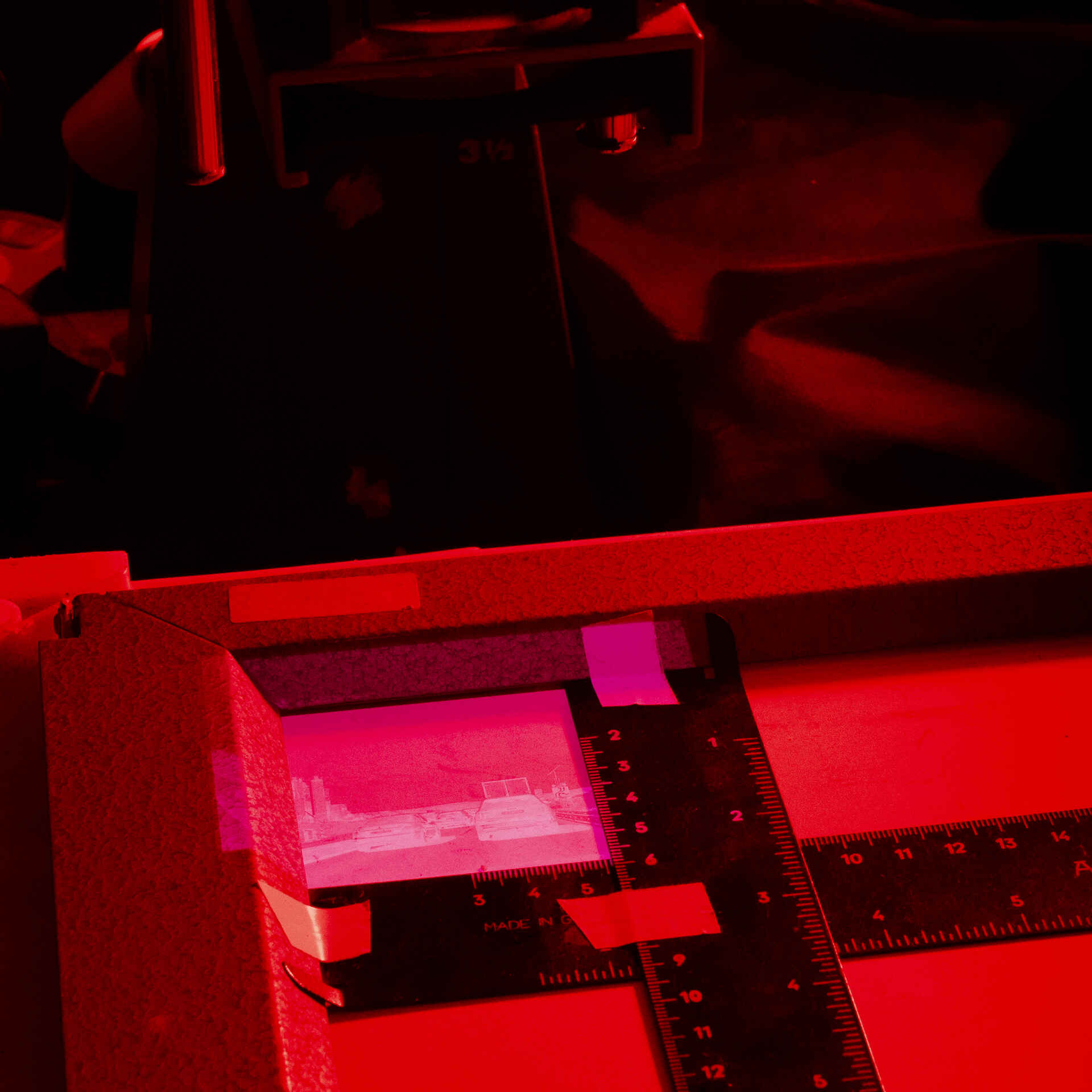 Vergrößern (Ilford HP5+ auf Fomatone MG Classic) (Foto: Martin Frech, 10/2025) Farbfoto: Das Bild zeigt das Belichten des Fotopapiers unter dem Vergrößerungsapparat bei Rotlicht. (Foto: Martin Frech, 10/2025)
