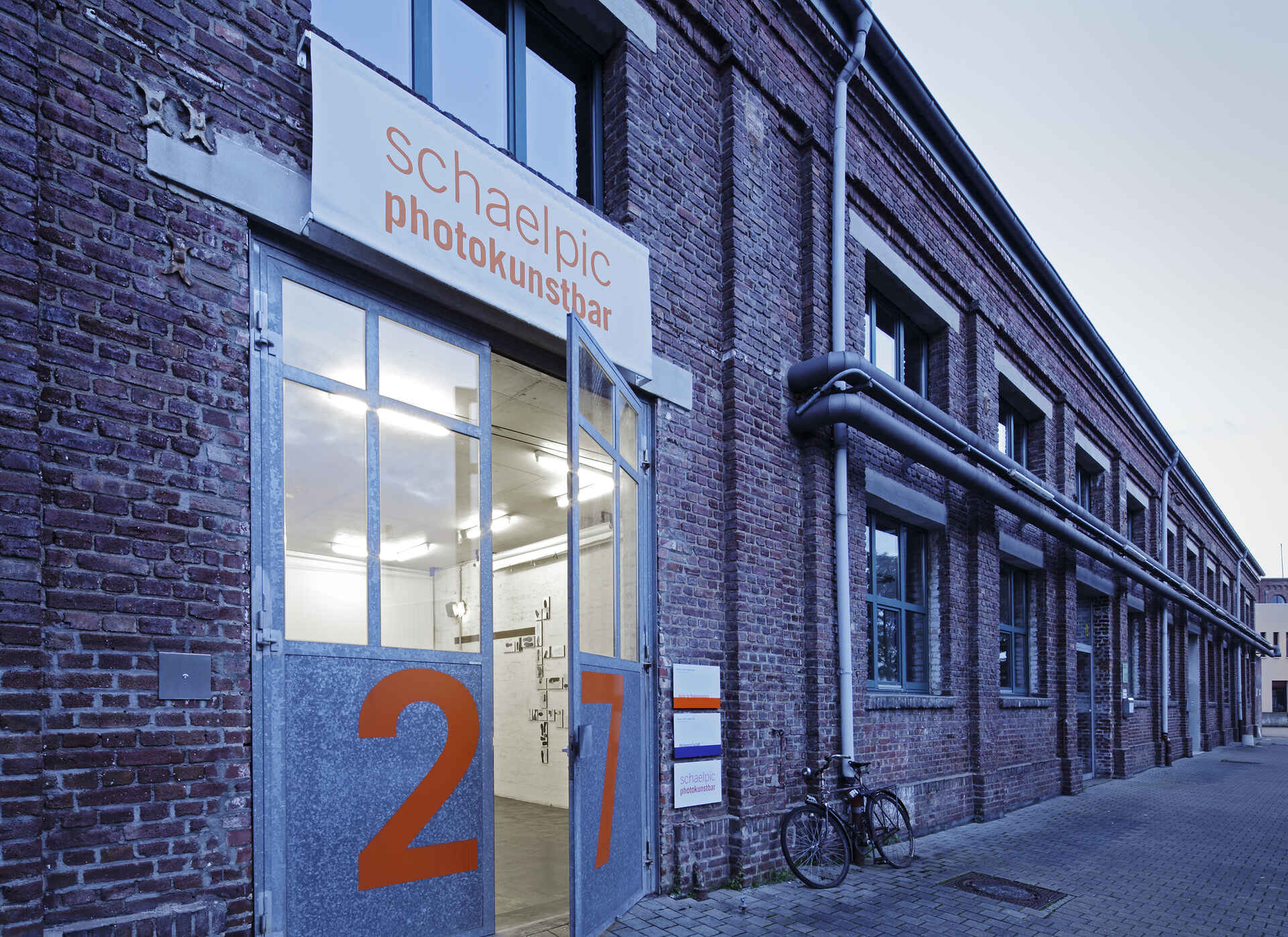 Farbbild: Außenansicht der schaelpic photokunstbar in Köln-Mülheim bei Dämmerung.