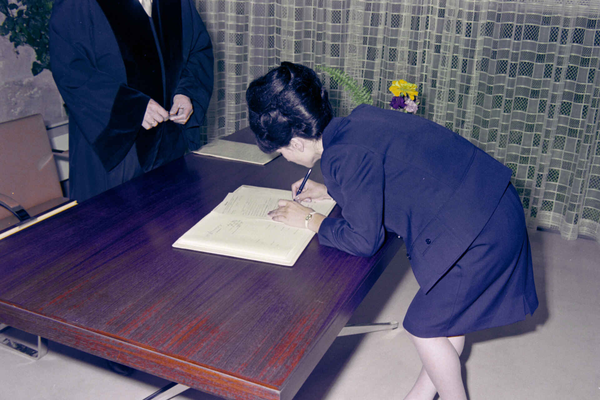 Szene auf dem Standesamt der Stadt Reutlingen (Foto: StadtA Rt./Dohm, 1967) Farbbild: Eine Frau unterschreibt eine Urkunde im Beisein einer Amtsperson. (Foto: StadtA Rt./Dohm, 1967)