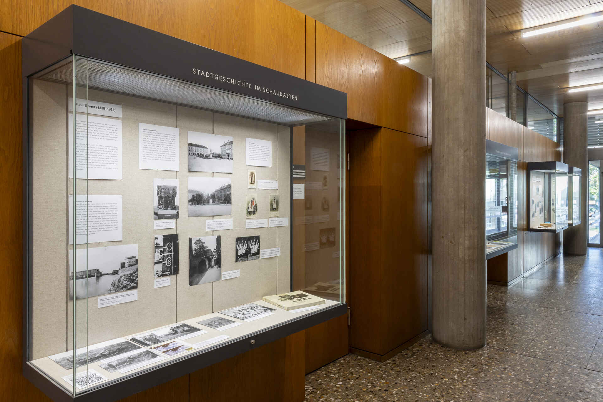 Farbbild (born-digital): Vitrine im Stadtarchiv Reutlingen mit der Ausstellung zu Paul Sinners 100. Geburtstag. (Foto: StadtA Rt./Frech, 9/2025)