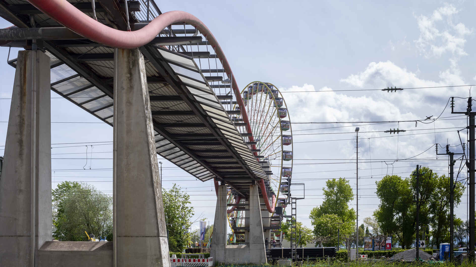 Sinuskurven-ähnliche Deko im Stadtbild (Foto: Martin Frech, 5/2021) Farbfoto: Fußgängerbrücke über Eisenbahngleise. (Foto: Martin Frech, 5/2021)