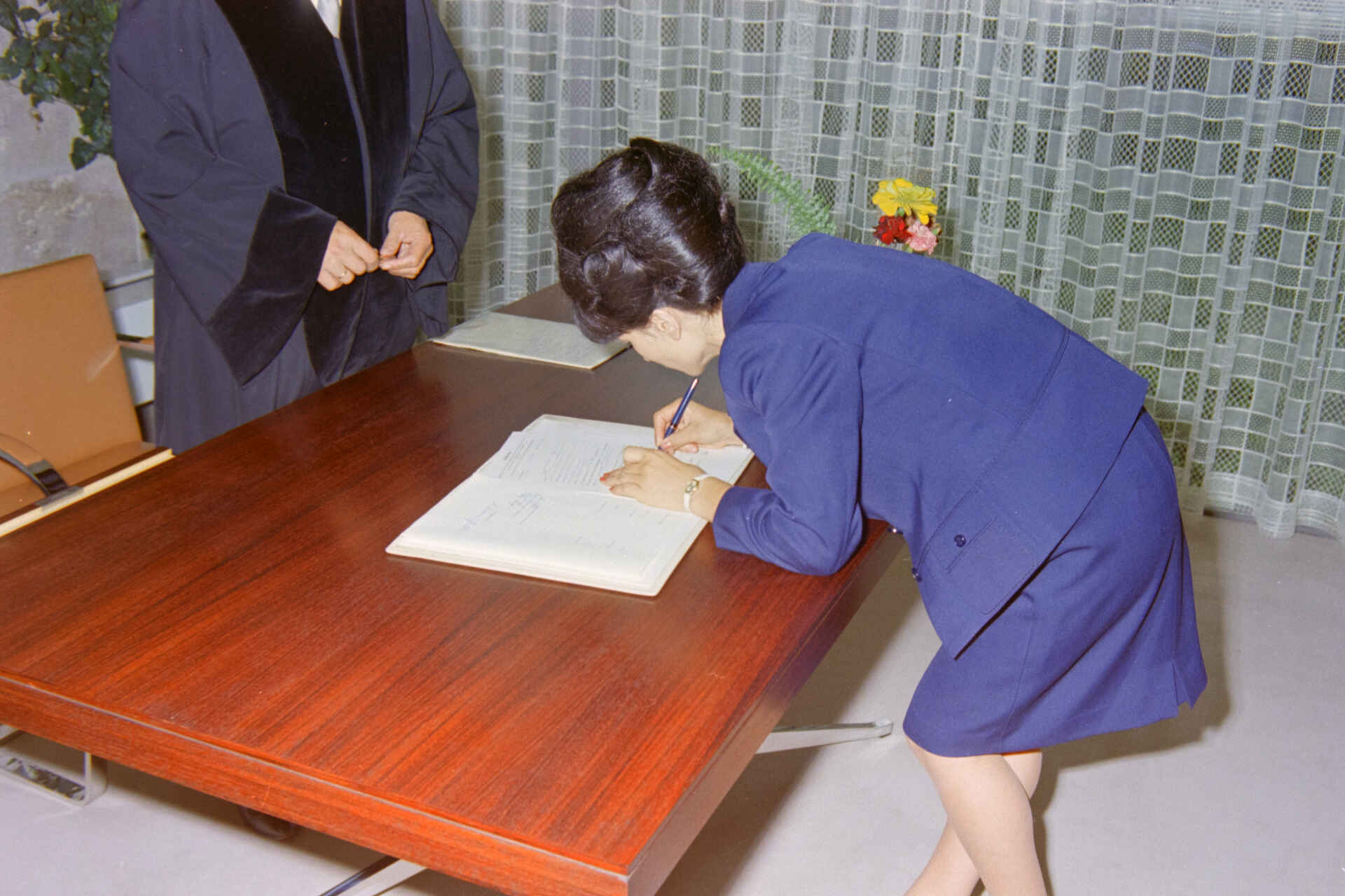 Szene auf dem Standesamt der Stadt Reutlingen (Foto: StadtA Rt./Dohm, 1967) Farbbild: Eine Frau unterschreibt eine Urkunde im Beisein einer Amtsperson. (Foto: StadtA Rt./Dohm, 1967)
