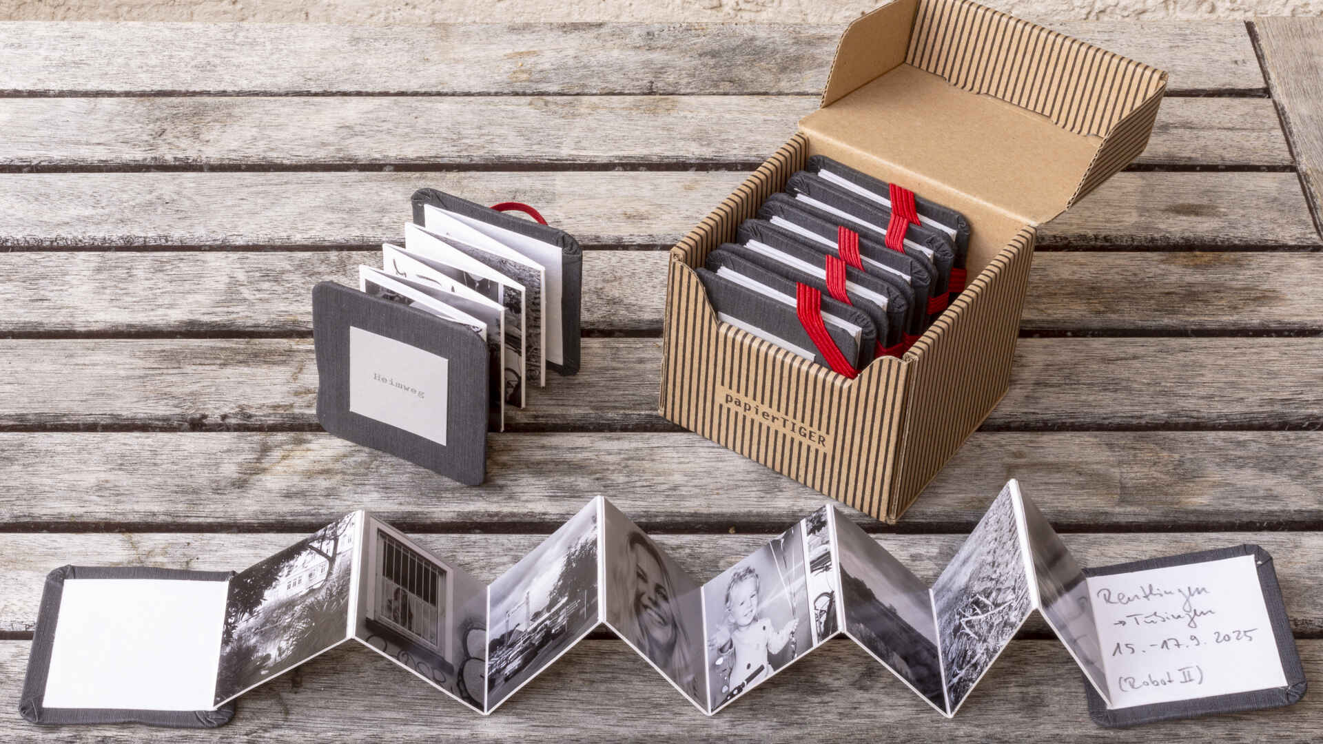 Eine kleinformatige Fotosammlung für unterwegs. (Foto: Martin Frech, 11/2025) Farbfoto: Zwei aufgefächerte Leporellos ›Heimweg‹ sowie ein Karteikästchen mit weiteren Leporellos. (Foto: Martin Frech, 11/2025)