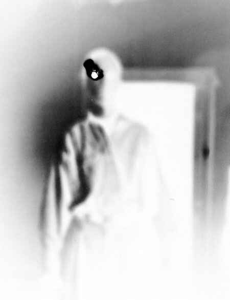 Papiernegativ einer Schwarzweiß-Lochkamera-Aufnahme: Menschliche Silhouette vor Türrahmen mit Loch im Fotopapier an der Position des Auges (Foto: Thomas Bachler, 1993)