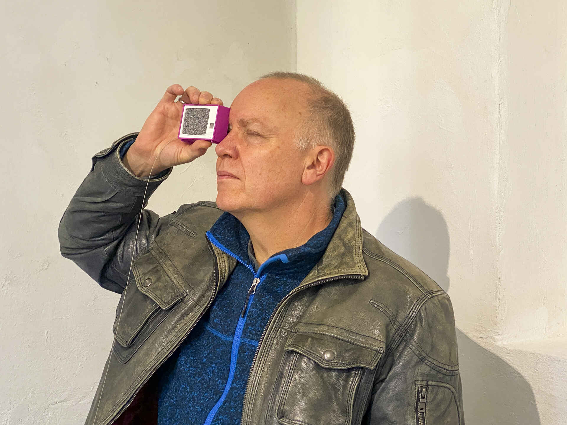 Farbbild (born-digital): Ein Mann schaut durch ein Plastiskop. (Foto: Tobias D. Kern, 11/2025)