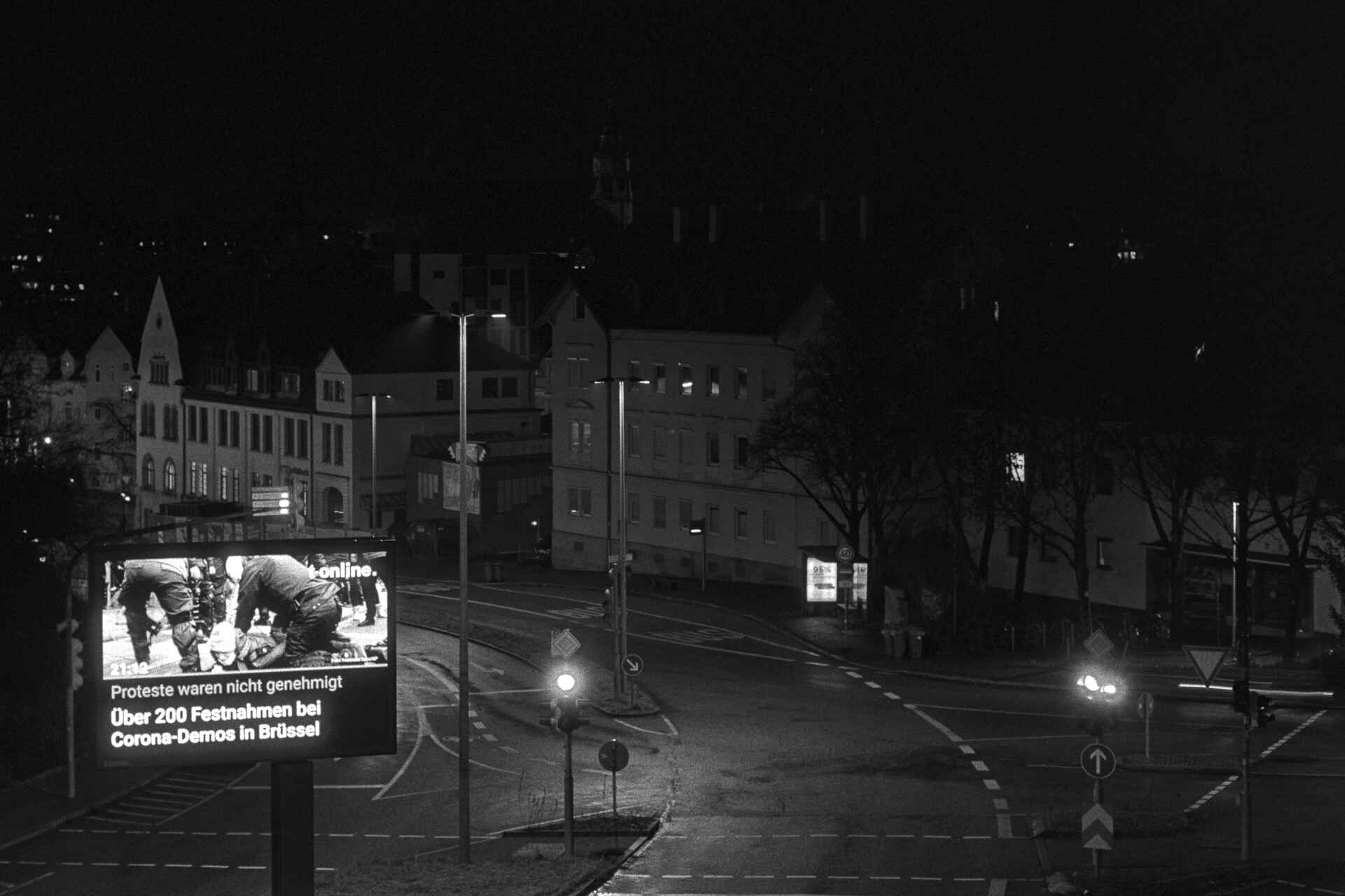 Schwarzweißbild (Scan vom Ilford-HP5+-Negativ): Nachricht über Festnahmen während einer Corona-Demonstration auf einer selbstleuchtenden Werbetafel in Tübingen. (Foto: Martin Frech, 1/2021)