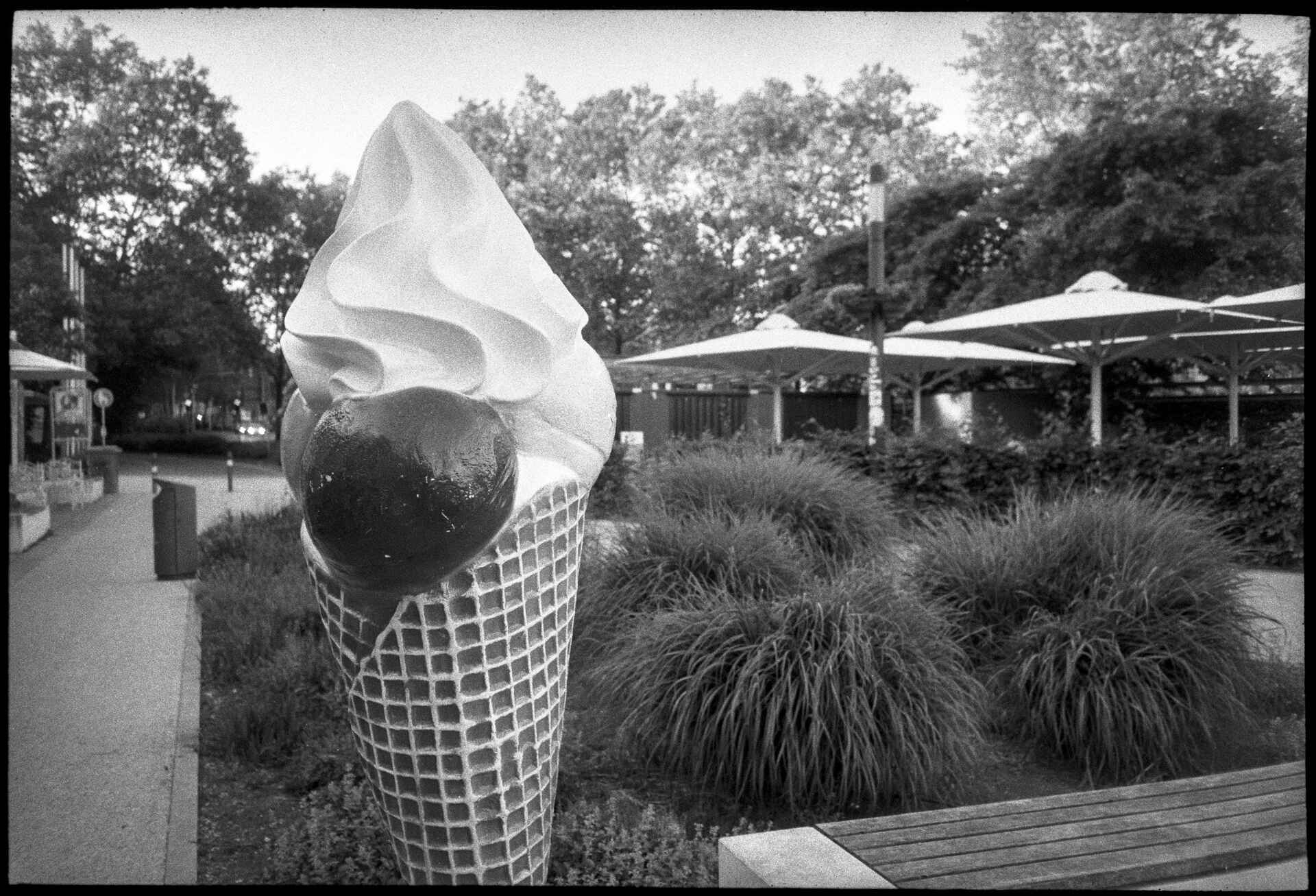 fast schon Sommer in Reutlingen (Foto: Martin Frech, 5/2026) Schwarzweiß (DSLR-Scan vom Kleinbild-Negativ): Eine übergroße Reklame-Eistüte neben dem Tübinger Tor in Reutlingen.