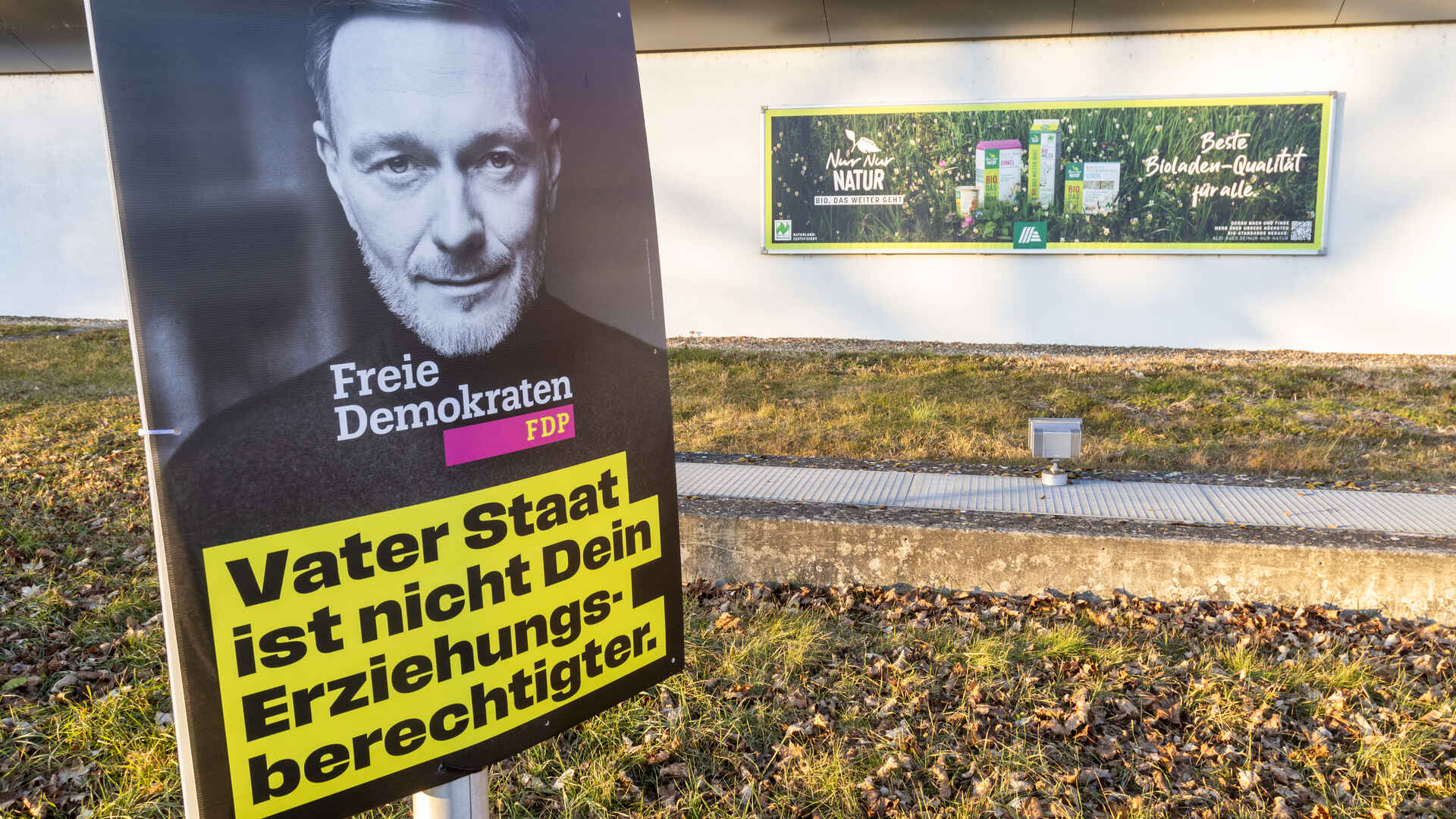 Farbbild (born-digital): Wahlplakat der Partei FDP in Tübingen zur Bundestagswahl 2025, im Hintergrund ein Werbeplakat für Bioprodukte. (Foto: Martin Frech, 1/2025)