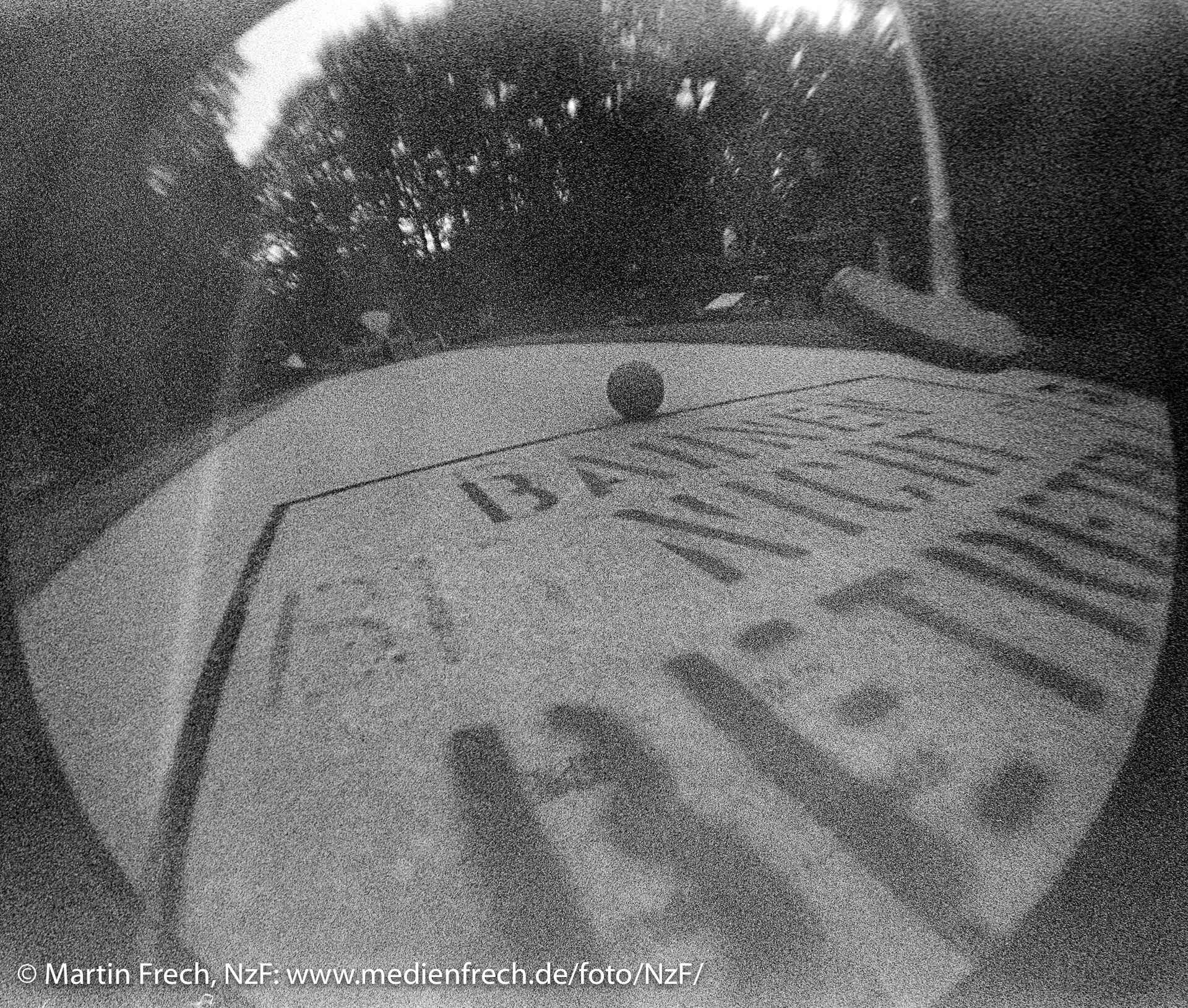 Fischaugen-Aufnahme mit der ›Lomo Fisheye [One]‹, schwarzweiß: Anfang einer Minigolf-Bahn mit Schläger und Ball in Berlin-Marienfelde. Schrift auf Bahn: Bahnen nicht betreten.